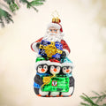 Santa Flurry Friends ornament. Santa is standing with three penguins in front of him, holding a gift with the Dave Thomas Foundation for Adoption logo on the front of it. View of front.