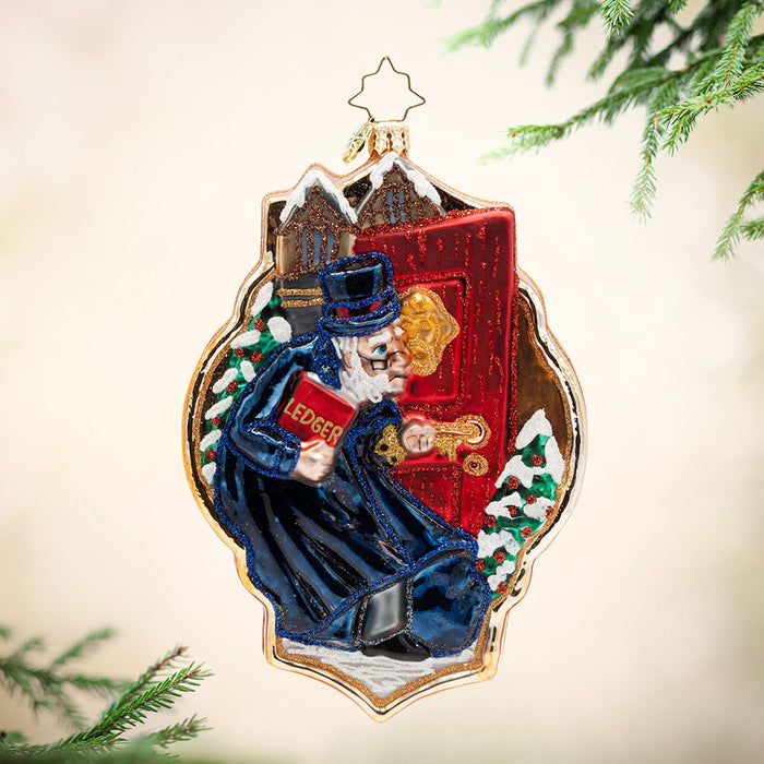A Knock from the Past. Ornament of Mr. Scrooge in a blue coat, standing in front of a red door and looking into a golden knocker. View of front