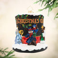 A Timeless Christmas Tale. A black top hat ornament covered in snow with the phrase "A Christmas Carol" in red and gold. Mr. Scrooge and the three ghosts also make an appearance around the hat. View of front