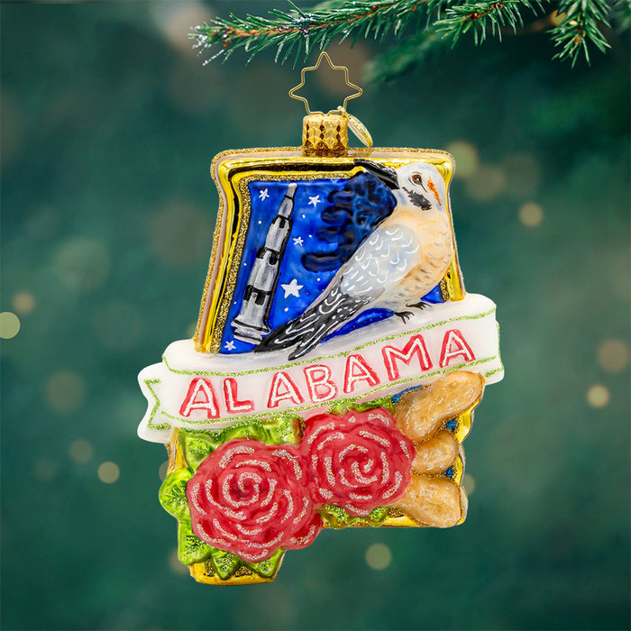 Ornament shaped as Alabama with a night sky, bird, two roses and a white banner with Alabama in red and white written on it. View of front