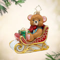 Beary Merry Sleigh. A red and gold ornament of a sleigh holding a sparkly brown bear and a green present. View of front.