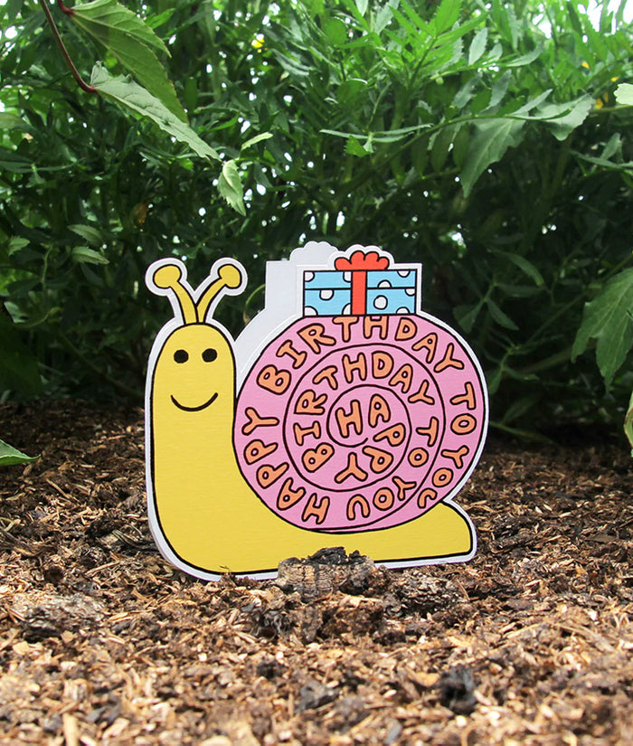 Colorful snail-shaped birthday card with 'Happy Birthday' text on a natural background