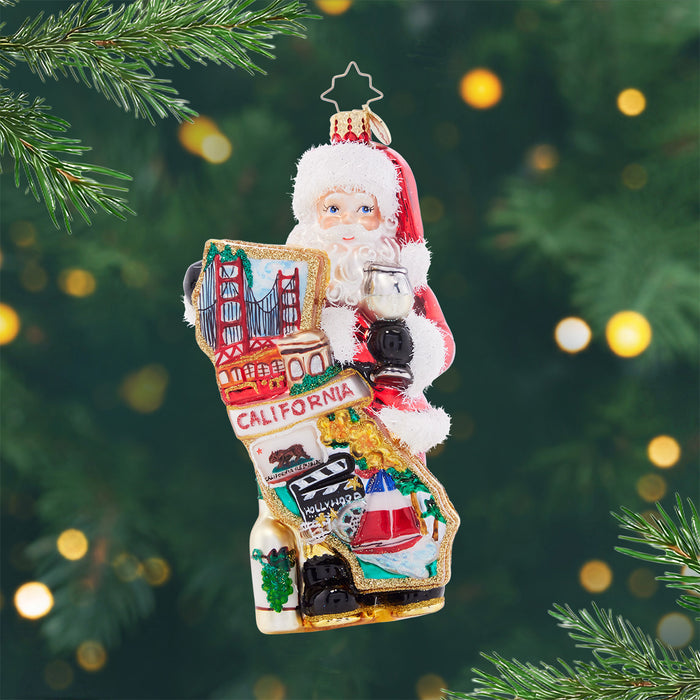 Cali Claus. Ornament of Santa holding the state of California that features the golden state bridge, Hollywood sign, and vineyards. View of front
