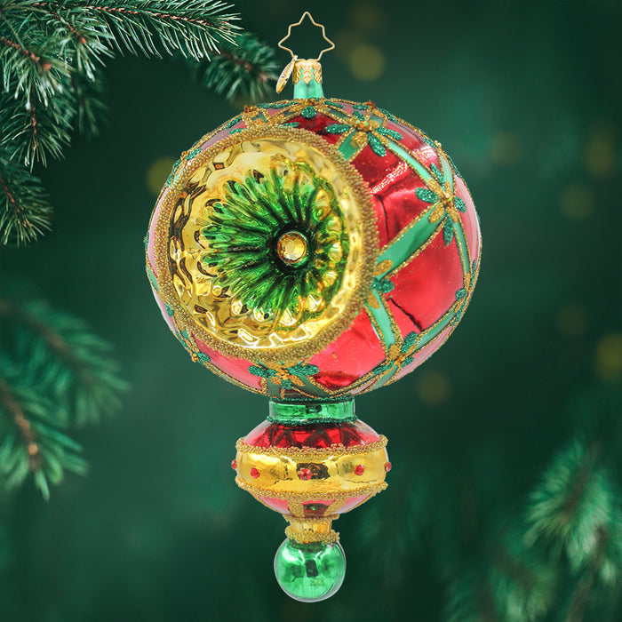 This ornament is a red and green orb with gold trim and star accents and below there is another round orb in red and gold with a hanging green globe. View of front