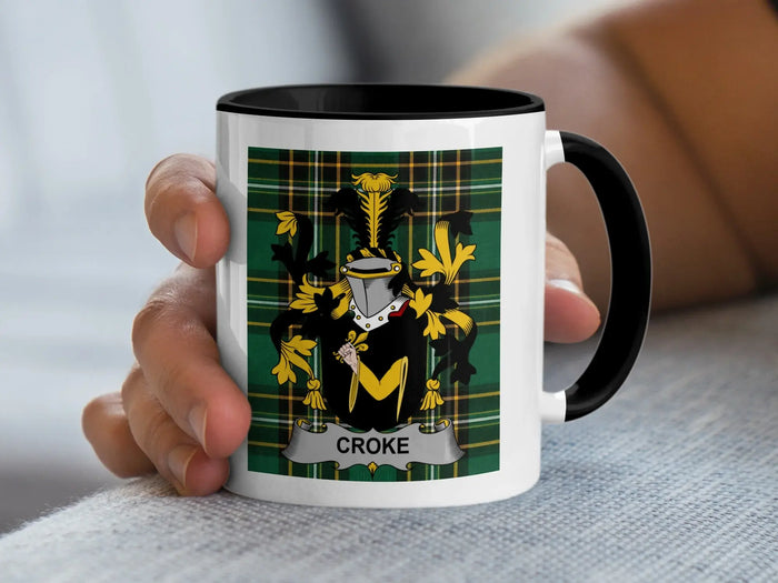 Mug with black rim displaying Croke coat of arms on green tartan background.