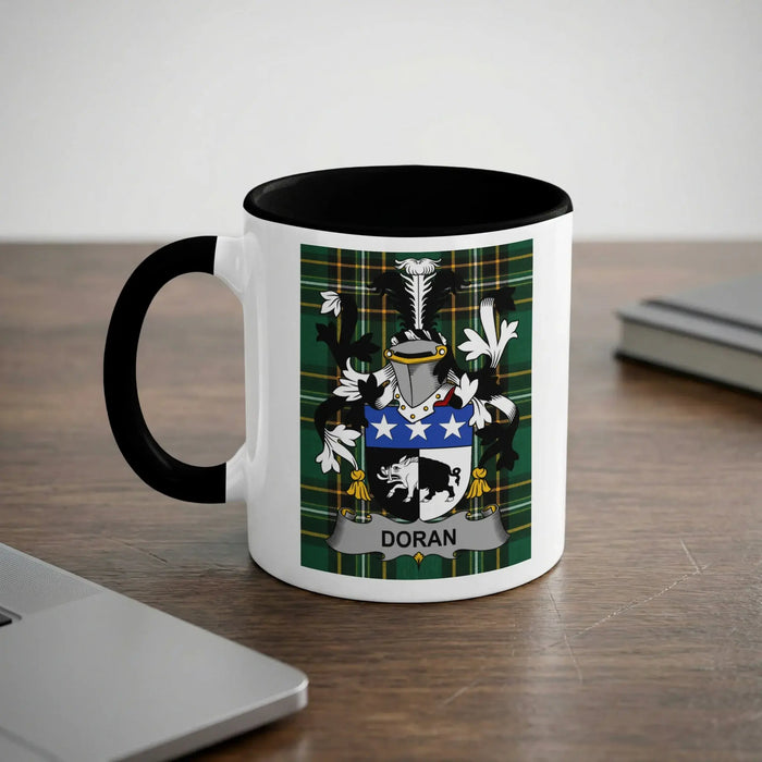 White mug with black rim and handle featuring Doran family crest on green plaid background.
