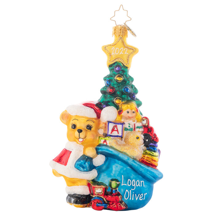 Ornament Description - First Glimpse: This baby bear has bag full of fun trailing behind him. Add a personal message or name on the bag to make this a truly unique gift. Note: Please allow approximately one month (on top of shipping time) for our elves to personalize your ornament.