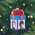 Gather Round for Gifting. Ornament in the shape of a present colored in blue with a big red bow at the top, and a different Beatle member on each side. View of front