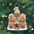 Gingerbread Manor Gem. Ornament of a gingerbread house in a sparkling brown with golden windows and red bows in front of them and a red door. View of front.