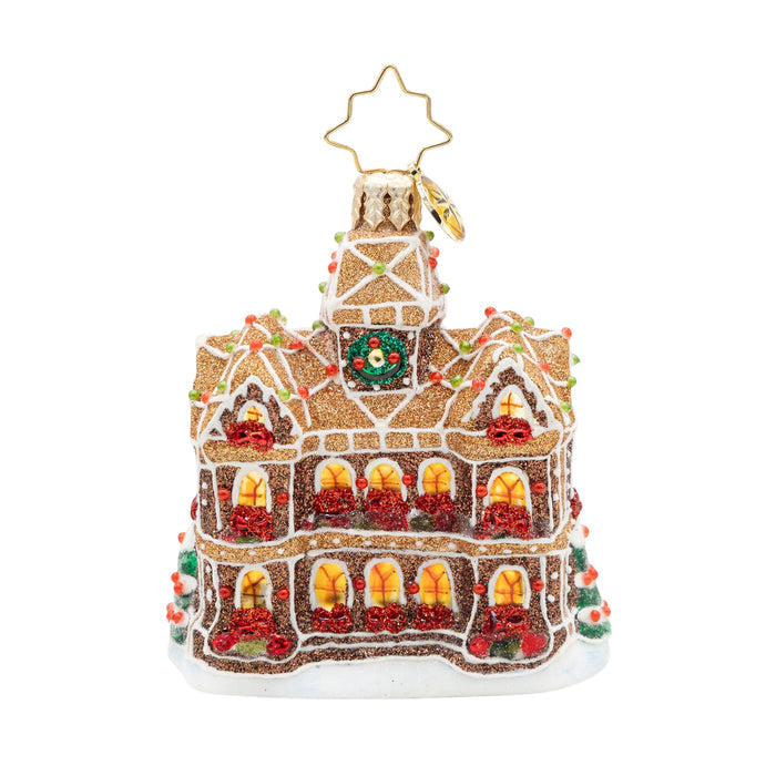 Back view ornament of a gingerbread house in a sparkling brown with golden windows and red bows in front of them and a red door.