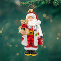 Front image - Healing Holiday Cheer - (Christmas ornaments) - Ornament of Santa in a doctor uniform while carrying a teddy bear and medical bag.
