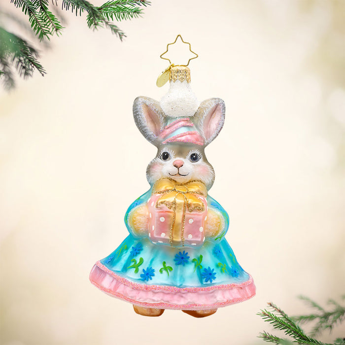 Hoppy Holiday ornament. This bunny is dressed in a blue and pink dress, with a gift in hand. View of front.