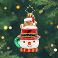 Hot Cocoa Delight Gem. Ornament of a sparkly brown gingerbread man popping out of a snowman mug in a red top hat. View of front