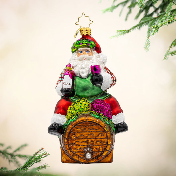 I Believe in Wine Santa ornament. Santa enjoys a glass of wine perched on a barrel. View of front.