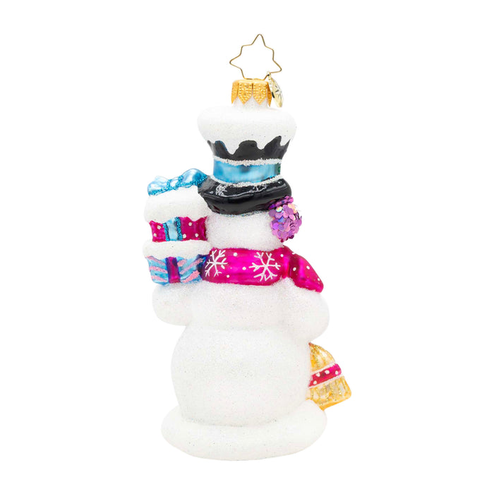 Back of a decorative ornament shaped liked a snowman holding two presents in the colors pink and blue in one had and in the other a broom.