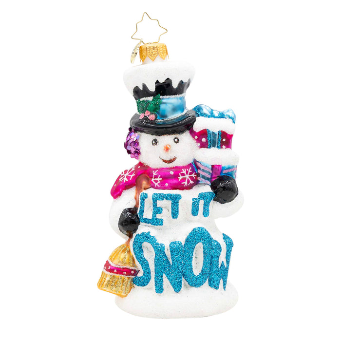 Front view of a ornament shaped like a snowman holding two presents in the colors pink and blue in one had and in the other a broom, with the phrase "Let It Snow" in blue on the front.