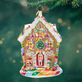 House shaped ornament adorned with details like gumdrops, candy canes, and frosting with colors of brown, white, pink, blue, green and yellow. View of front