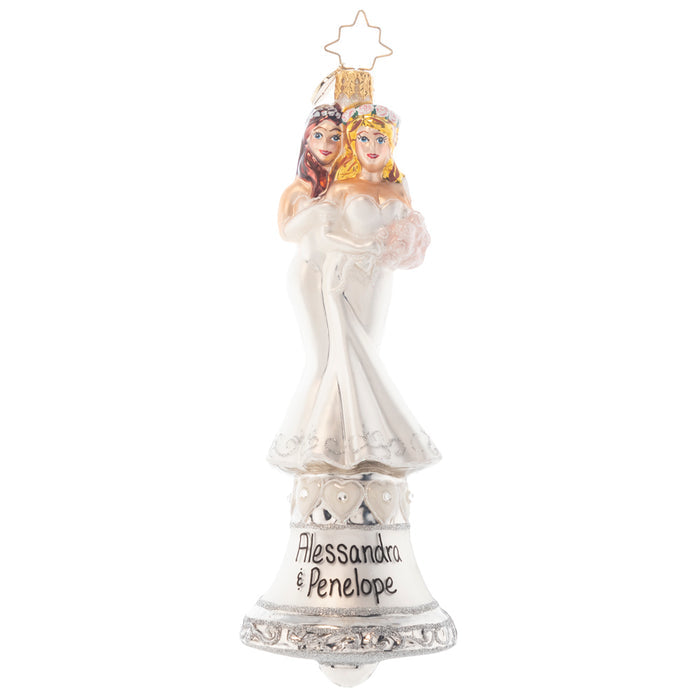 Ornament Description - Passionately Perfect: This lovely couple stands together atop a silver bell, ready to ring in the start of their new relationship! Don't they look beautiful in their matching wedding dresses? Note: Please allow approximately one month (on top of shipping time) for our elves to personalize your ornament.