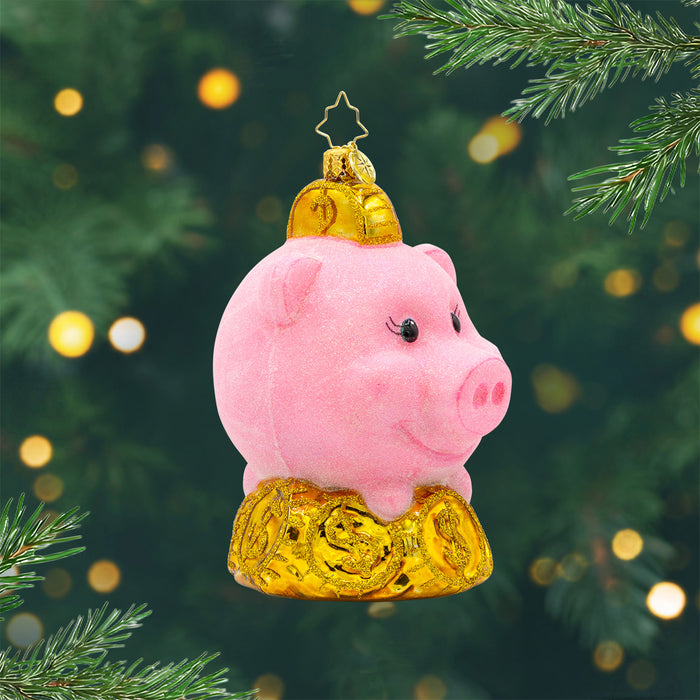 Ornament of a piggy bank with bright pink color, and sparkling gold coins beneath it. View of front