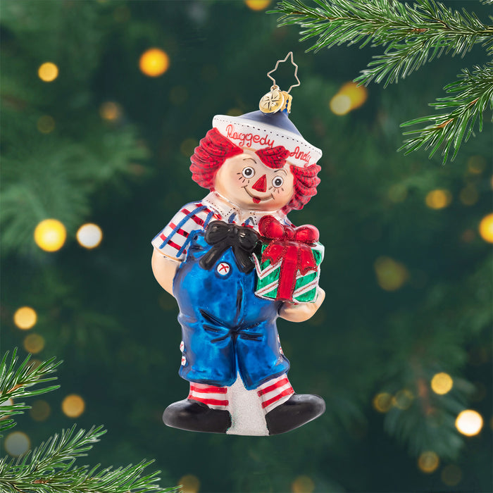 Raggedy Presents. ornament of a Raggedy Andy dol l holding a green present. View of front