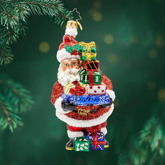 Santa's Surprise Stash ornament.  Features Santa carrying a tower of  festive presents. View of front.