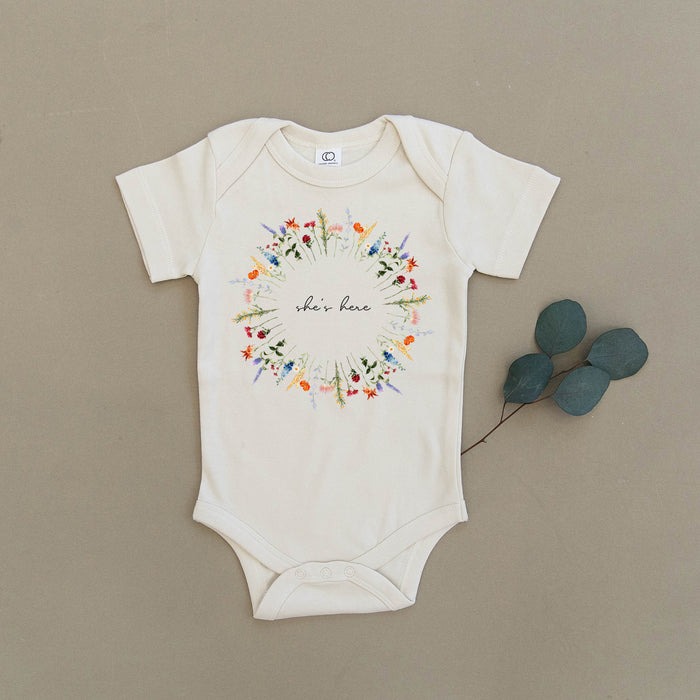 She's Here Wildflower Floral Wreath Organic Baby Onesie®