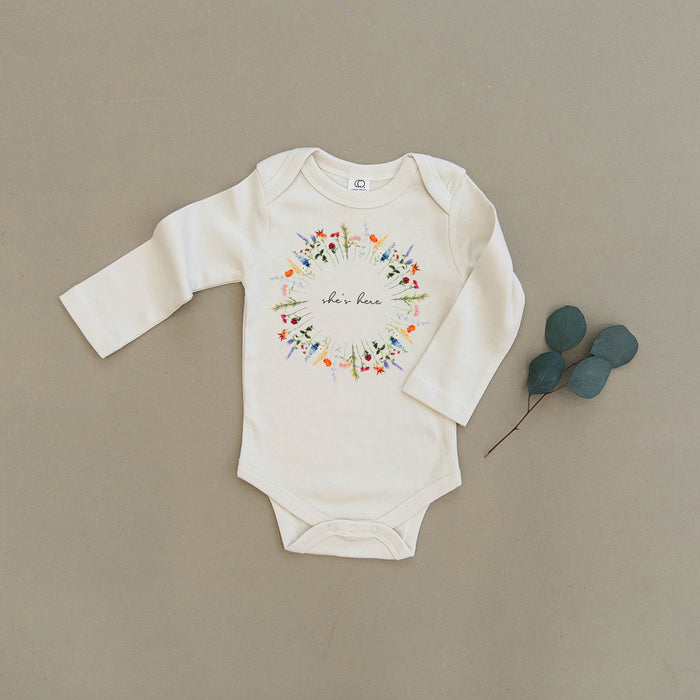 She's Here Wildflower Floral Wreath Organic Baby Onesie®