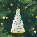 Six-Tier Celebration Gem. Cake shaped ornament with a white base and a mix of pink, purple, and yellow flowers. View of front
