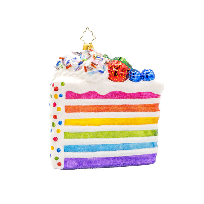 Slice of Joy ornament. A tall slice of rainbow layered cake with sprinkles and fruit on top. View of front.