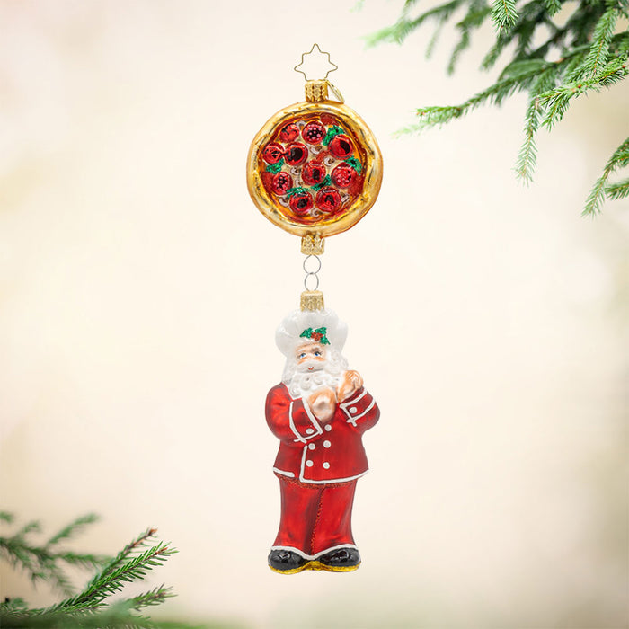 St. Nick's Pizza Delight ornament. Santa in a red chef's outfit dangles from a large pepperoni pizza pie. View of front.