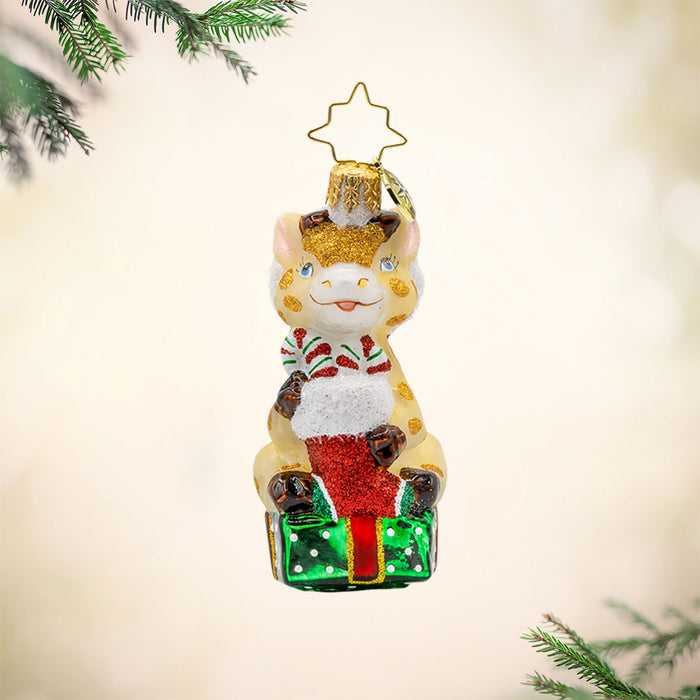 Stacked with Sweetness Gem ornament. A giraffe sits atop a gift with a stocking full of candy canes in hand. View of front.
