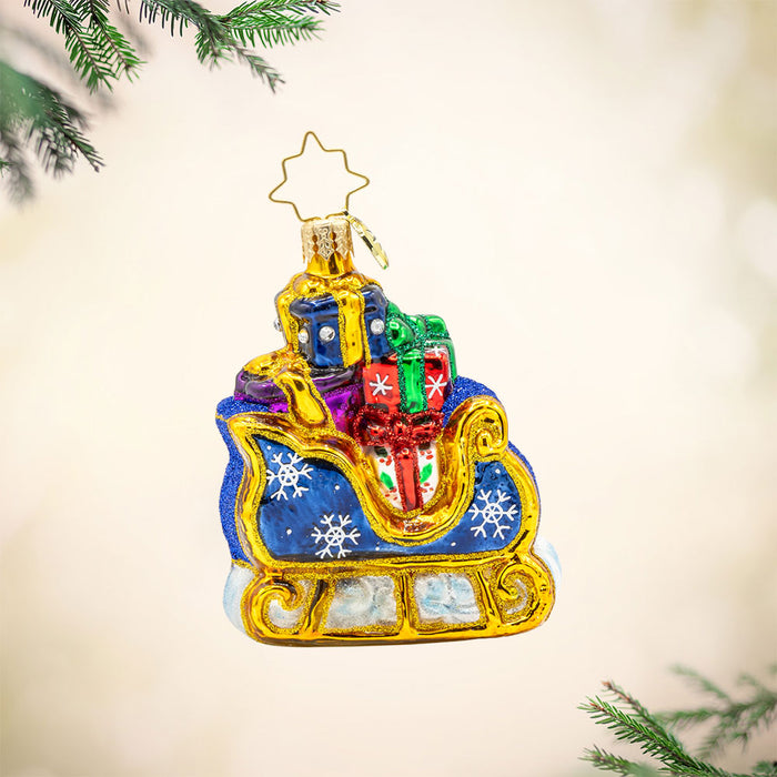 Starry Night Sleigh Gem ornament. A blue sleigh with gold trim, piled high with gifts. View of front.