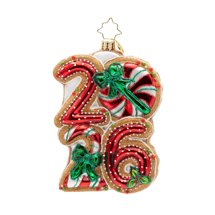 Front view of ornament of the year 2026 in peppermint colors and white polka dots with three green bows and gold outlining.