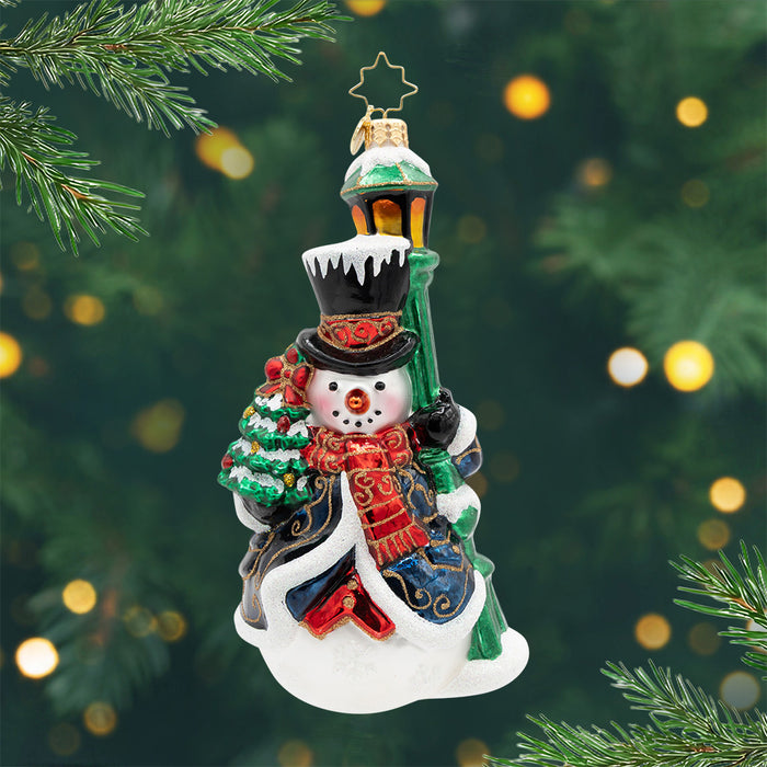 The Holiday Gentlemen. Ornament. A snowman dressed in a blue robe and standing next to a green light post. View of front.