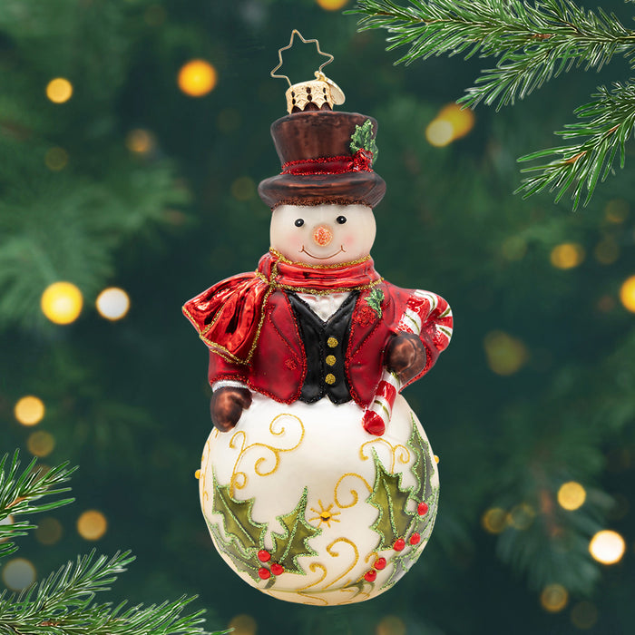 The Jingle Gent. A snowman ornament dressed in a red tailored top coat and hat with a decorated base of two green mistletoes. View of front