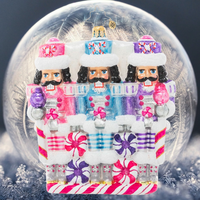 Ornament Description - The Sweetest Trio: A trio of nutcrackers smile dutifully from their posts, dressed in uniforms of wintry pastels. Someone's got to guard the North Pole candy stash, and three heads are better than one!